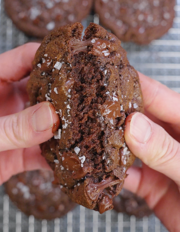 Double chocolate brown butter cookie pulled apart to reveal a fudgy, brownie-like center with melted dark chocolate throughout.