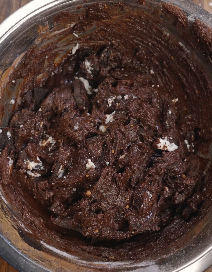 Chopped Oreo cookies folded into rich chocolate brownie batter, evenly distributing cookie pieces throughout the mixture.