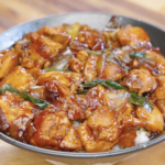 Finished Chicken Onion Stir Fry coated in a glossy soy sauce glaze served over a bowl of steamed white rice.