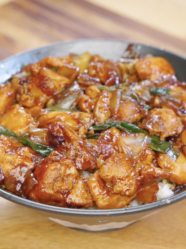 Finished Chicken Onion Stir Fry coated in a glossy soy sauce glaze served over a bowl of steamed white rice.