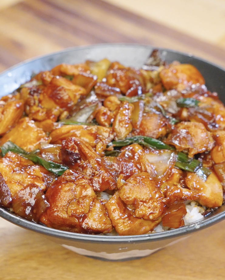 Finished Chicken Onion Stir Fry coated in a glossy soy sauce glaze served over a bowl of steamed white rice.