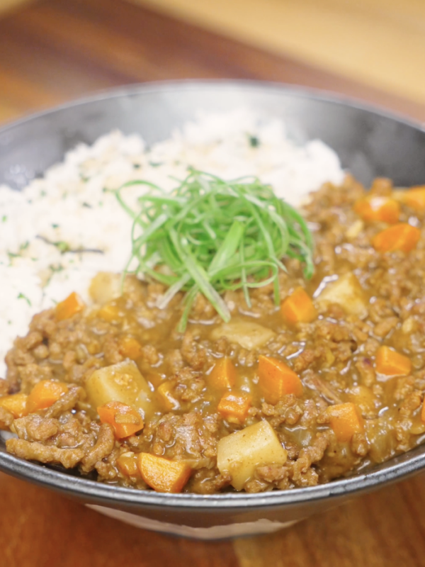 Finished bowl of Japanese ground beef curry made with tender ground beef, carrots, potatoes, and a rich curry sauce, served with fluffy white rice and topped with sliced scallions.