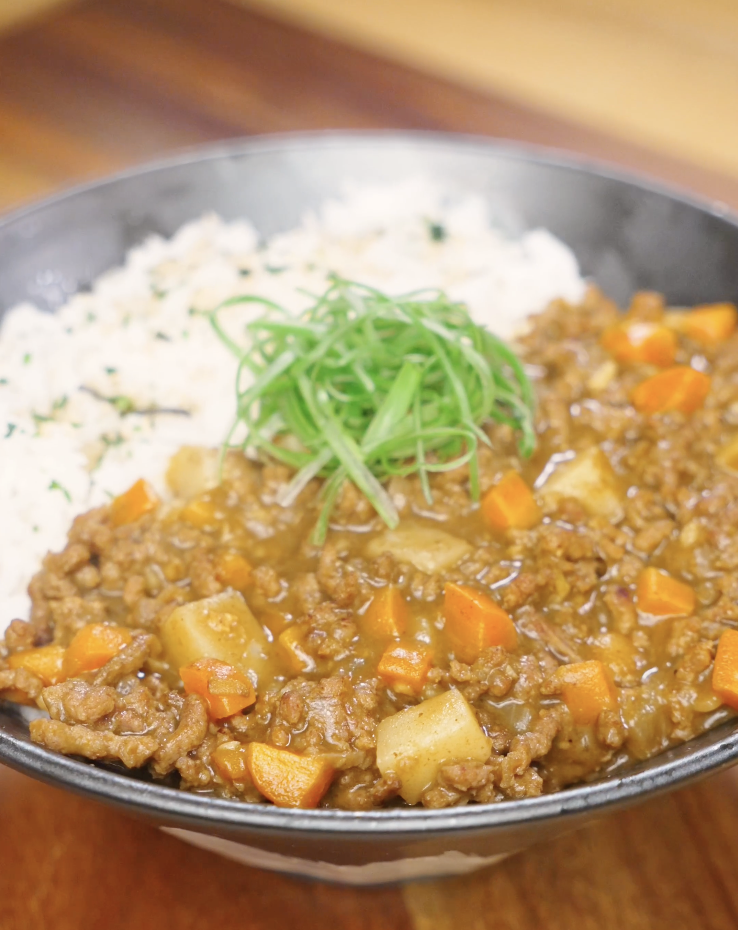 Finished bowl of Japanese ground beef curry made with tender ground beef, carrots, potatoes, and a rich curry sauce, served with fluffy white rice and topped with sliced scallions.