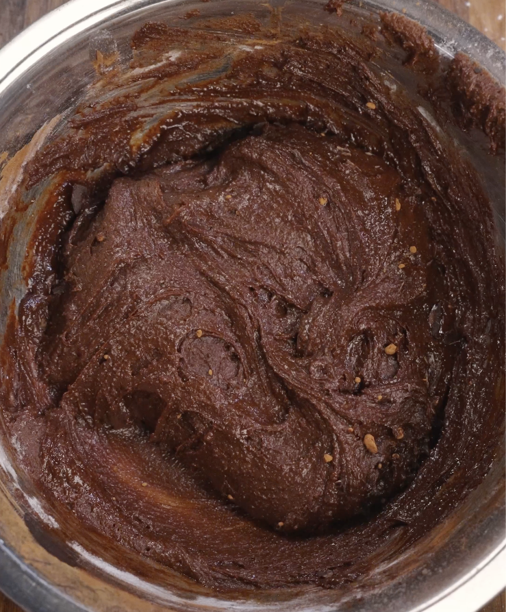 Thick chocolate brownie batter fully mixed until smooth and uniform, forming the base before adding Oreos and chocolate chunks.