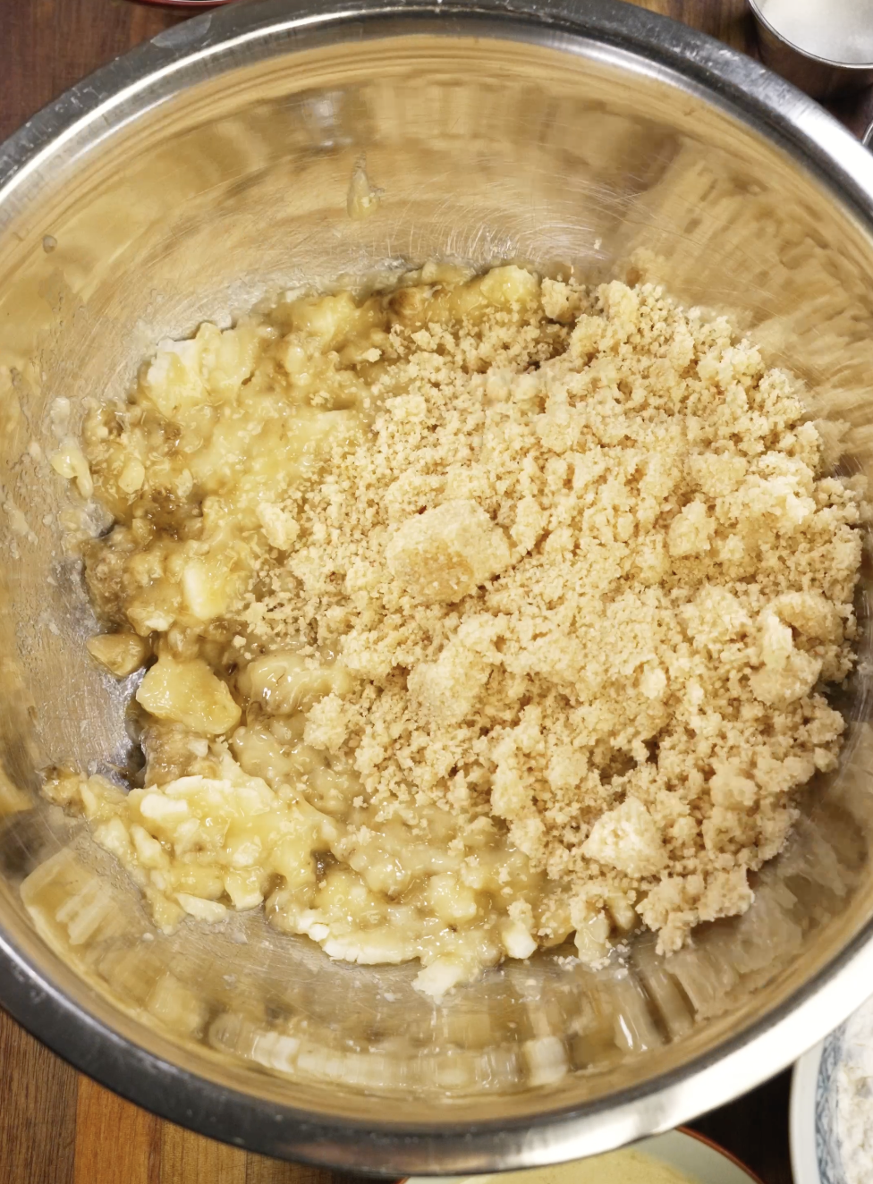 Mashed ripe bananas mixed with brown sugar in a large bowl, creating a thick and glossy base for homemade chocolate chip banana bread.