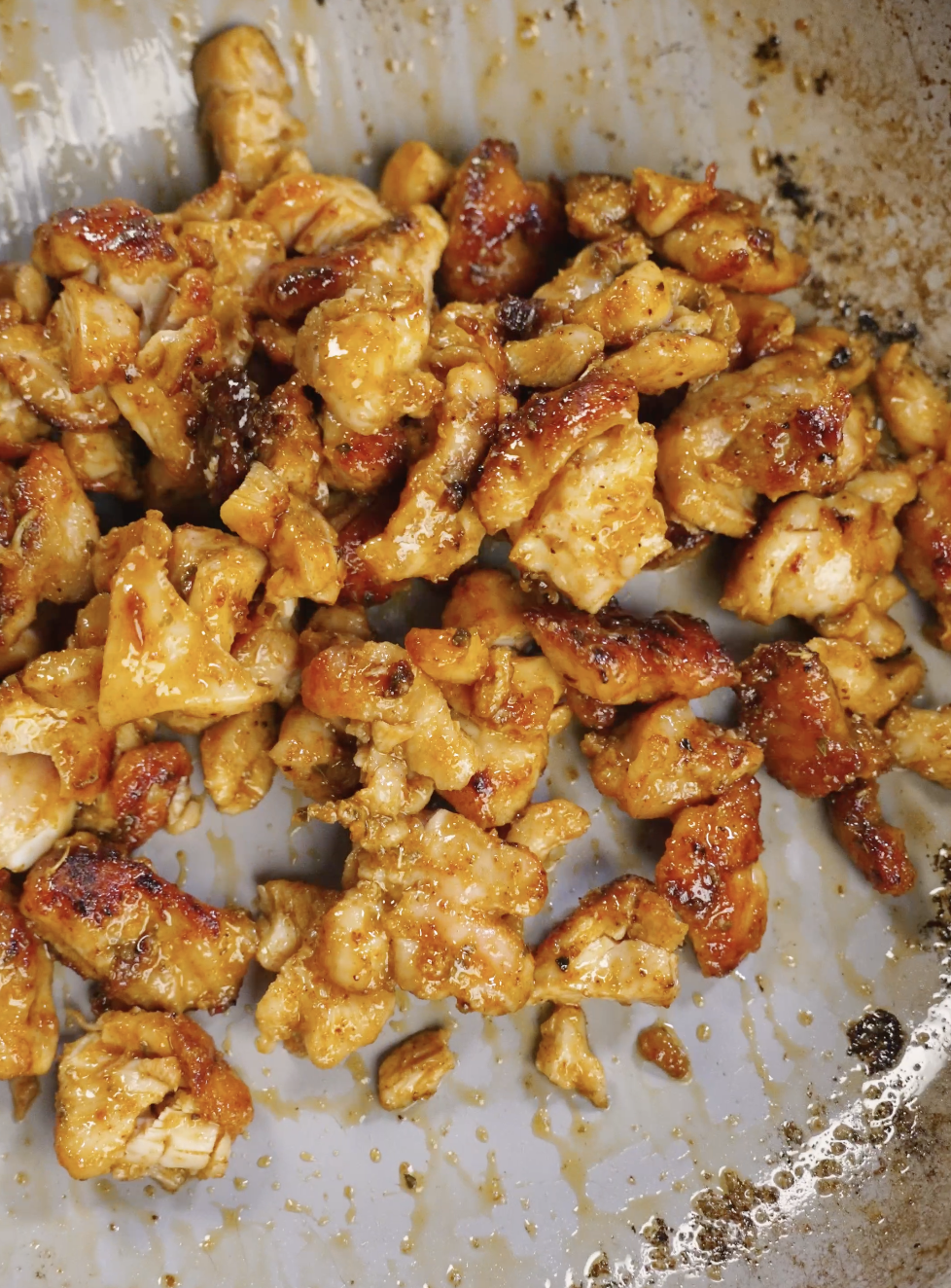 Seasoned chicken thigh pieces cooking in a hot skillet until golden brown and caramelized, developing crispy edges for homemade crispy chicken tacos.