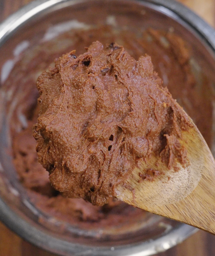 Double chocolate brown butter cookie dough scooped into even portions on parchment paper before baking.