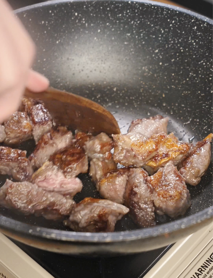 Beef cubes searing in a nonstick pan until browned and caramelized, building flavor and texture for soy garlic beef before adding the sauce.