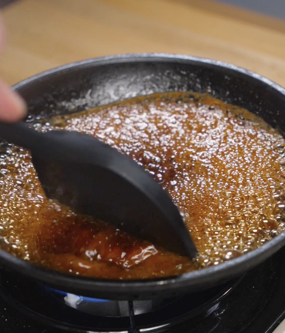 Soy garlic sauce bubbling and reducing in a small pan on the stove, thickening into a glossy glaze that will coat the crispy Korean chicken.