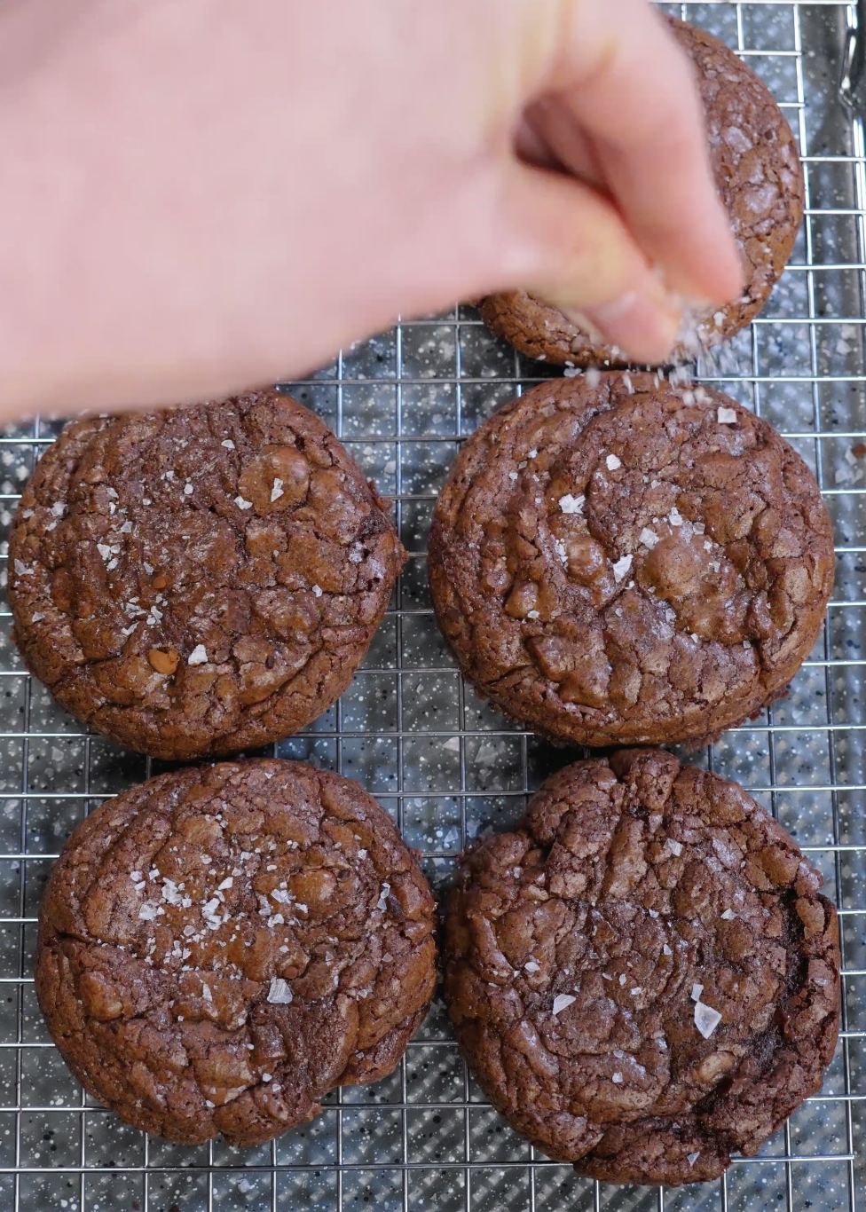 Flaky sea salt sprinkled over warm brownie cookies to enhance chocolate flavor and balance sweetness.