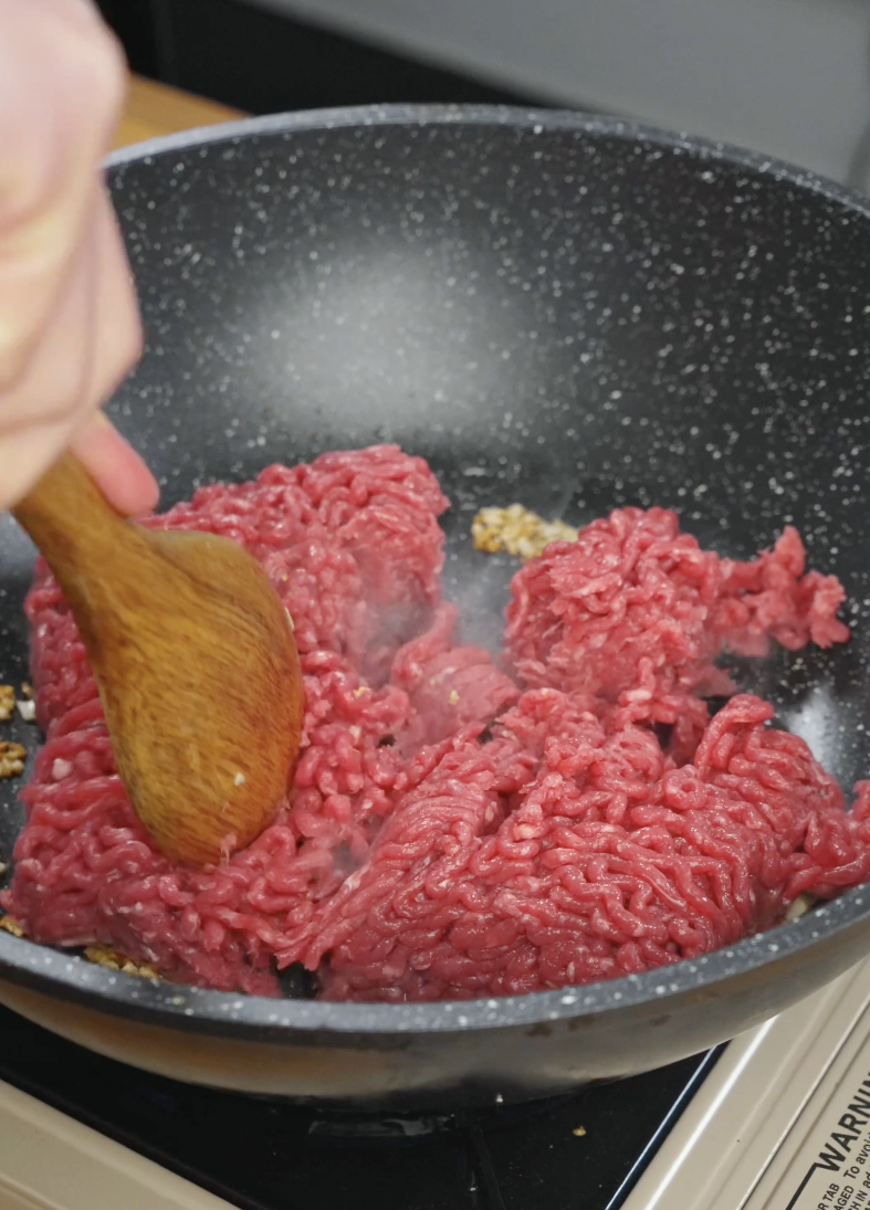 Ground beef being broken apart in a pan as it cooks for Korean ground beef recipe.