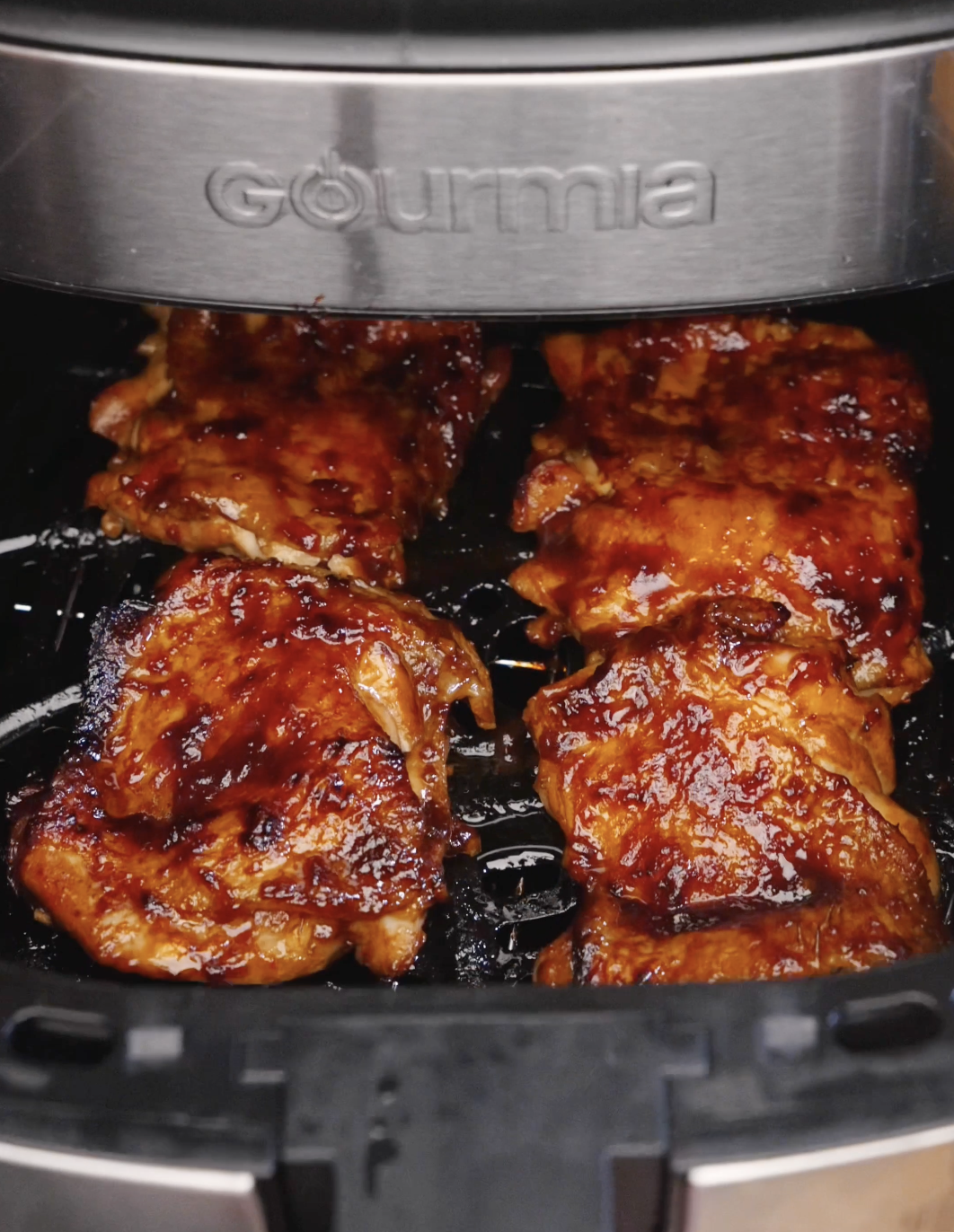 Marinated chicken thighs caramelizing inside an air fryer basket while cooking Sweet Chili Chicken.