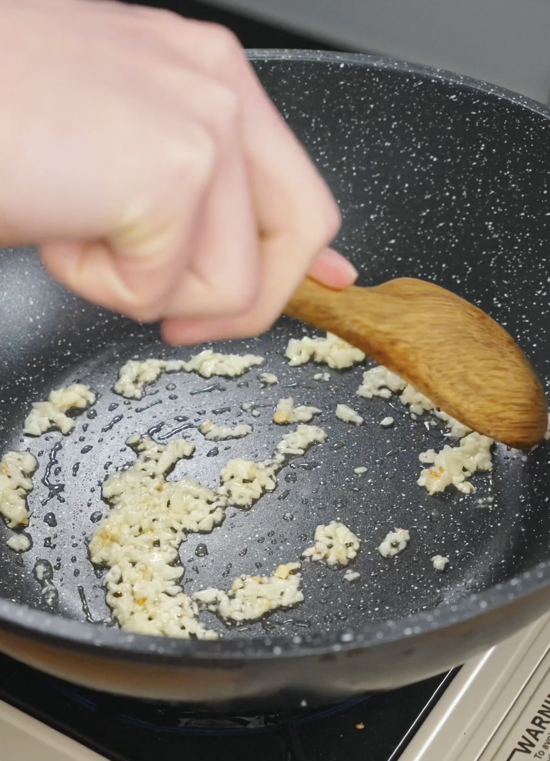 Minced garlic saut&eacute;ing in a pan with oil to start Korean ground beef recipe.