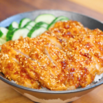 Sliced crispy garlic chicken glazed in soy garlic sauce and topped with sesame seeds served over steamed rice with sliced cucumbers.