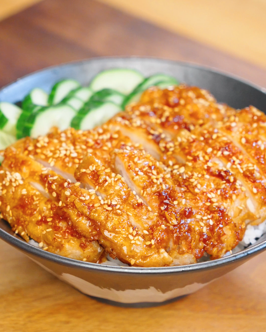Sliced crispy garlic chicken glazed in soy garlic sauce and topped with sesame seeds served over steamed rice with sliced cucumbers.