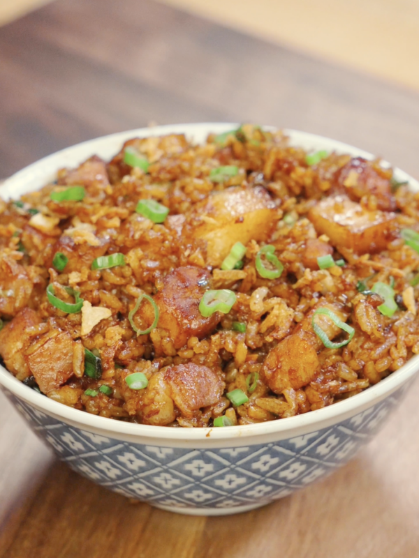 Bowl of garlic pork belly fried rice topped with scallions and crispy onions for extra flavor and texture.