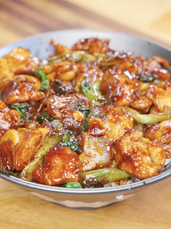 Bowl of honey garlic chicken stir fry with caramelized chicken, onions, garlic, and scallions served over steamed rice.