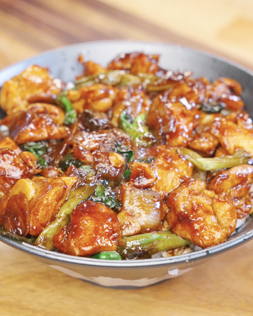 Bowl of honey garlic chicken stir fry with caramelized chicken, onions, garlic, and scallions served over steamed rice.