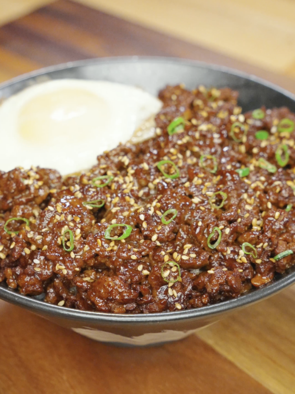 Bowl of Korean ground beef recipe served over rice with sesame seeds scallions and a fried egg.