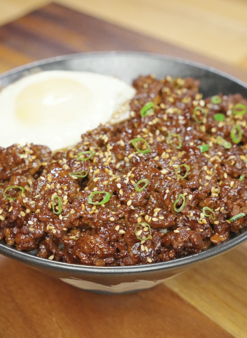 Bowl of Korean ground beef recipe served over rice with sesame seeds scallions and a fried egg.
