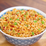 Bowl of garlic sesame noodles tossed in creamy sesame sauce and topped with chili flakes, sesame seeds, and sliced scallions.