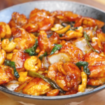 Bowl of honey cashew chicken with glossy honey soy glazed chicken, roasted cashews, scallions, and onions served over steamed white rice.