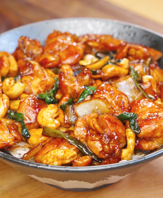 Bowl of honey cashew chicken with glossy honey soy glazed chicken, roasted cashews, scallions, and onions served over steamed white rice.