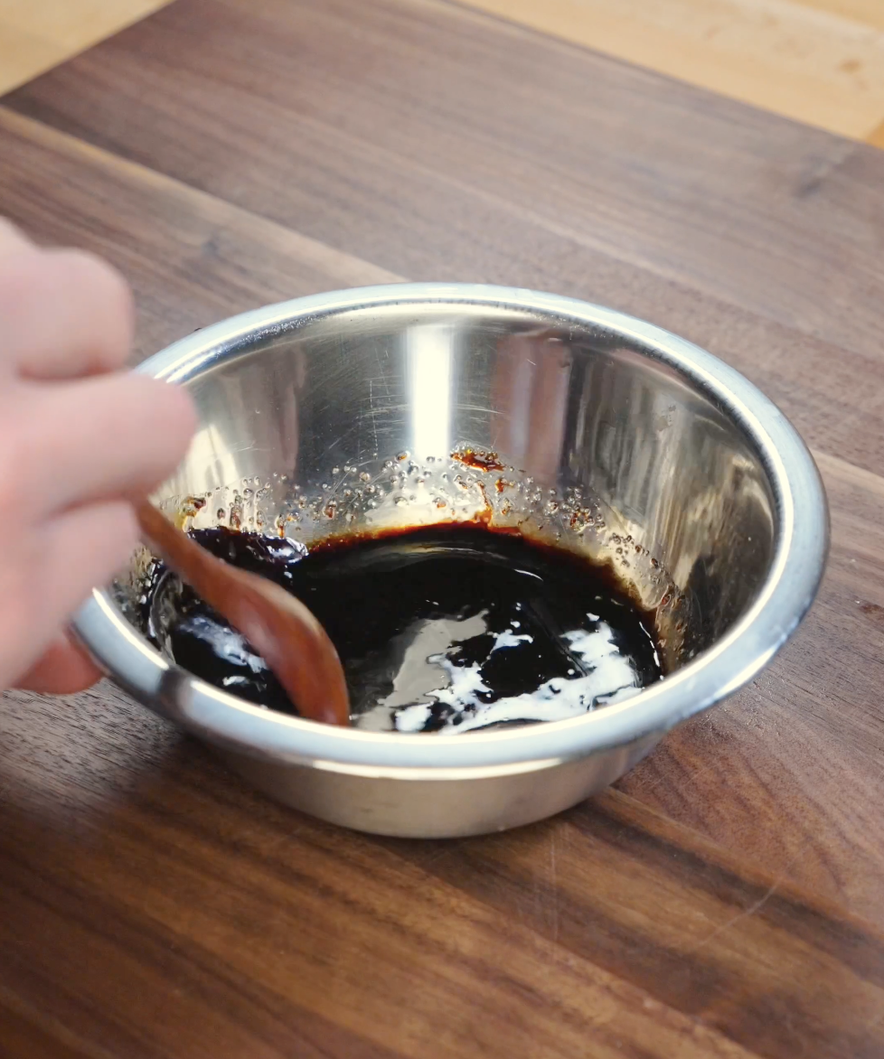 Dark soy sauce, light soy sauce, oyster sauce, sesame oil, sugar, and white pepper being stirred together in a bowl for fried rice sauce.