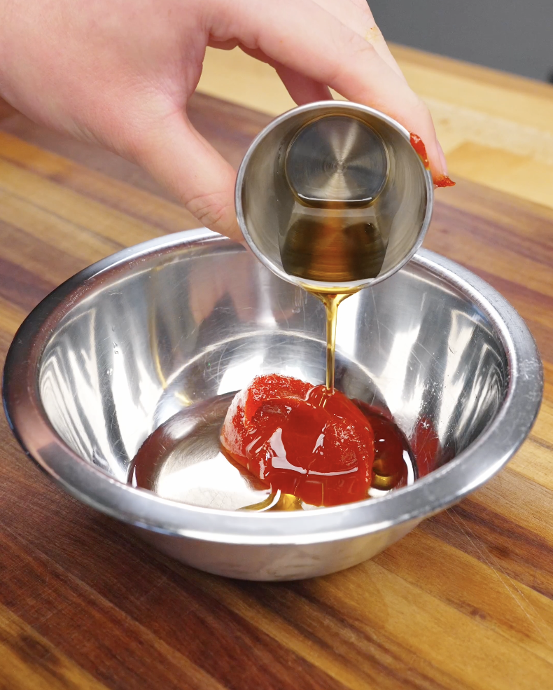 Gochujang sauce being poured into a bowl with oil and seasonings to make sauce for beef bibimbap recipe.