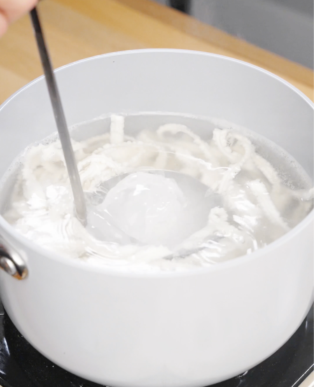 A ladle reserves starchy noodle water for Garlic Chili Noodles to help thicken and emulsify the sauce.