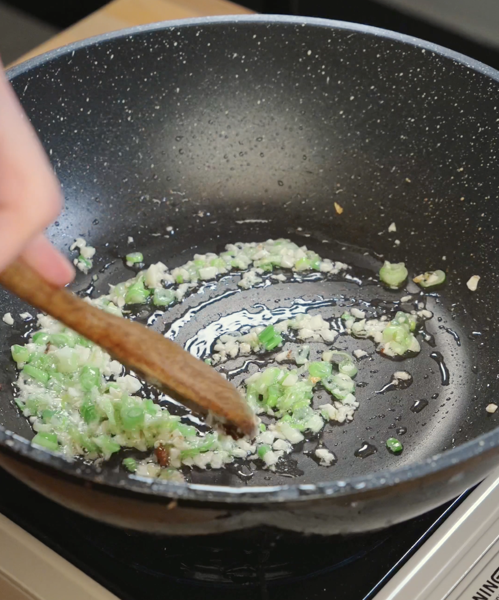 Minced garlic and chopped scallion whites cooking in rendered pork fat to build the aromatic base for garlic pork belly fried rice.