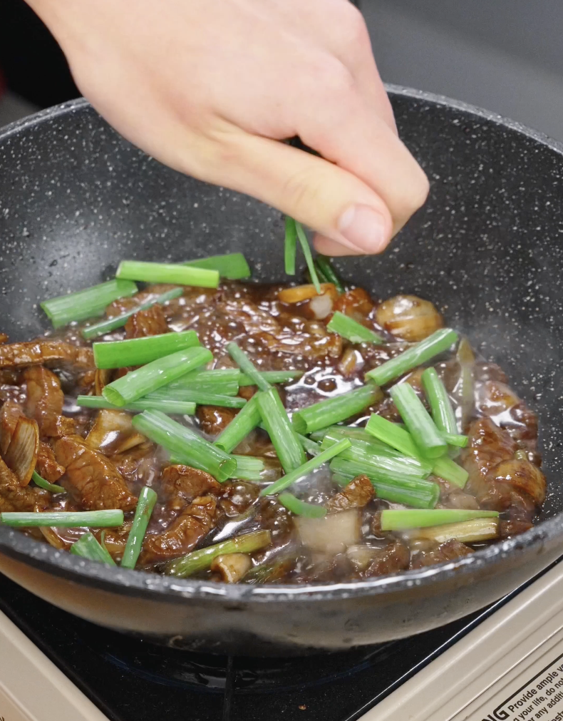 Fresh scallion greens being added to the stir fry as the Mongolian Beef Recipe finishes cooking.