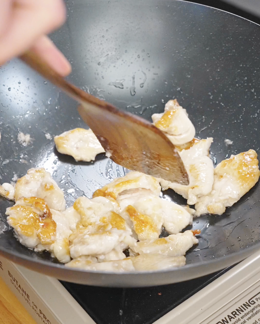 Marinated chicken pieces being seared in a pan until lightly browned, starting the cooking process for chicken chow mein.