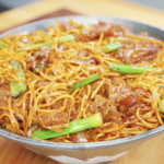 Bowl of beef chow mein with noodles, onions, and scallions tossed in a rich glossy sauce in the Beef Chow Mein Recipe.