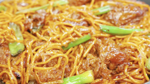 Bowl of beef chow mein with noodles, onions, and scallions tossed in a rich glossy sauce in the Beef Chow Mein Recipe.
