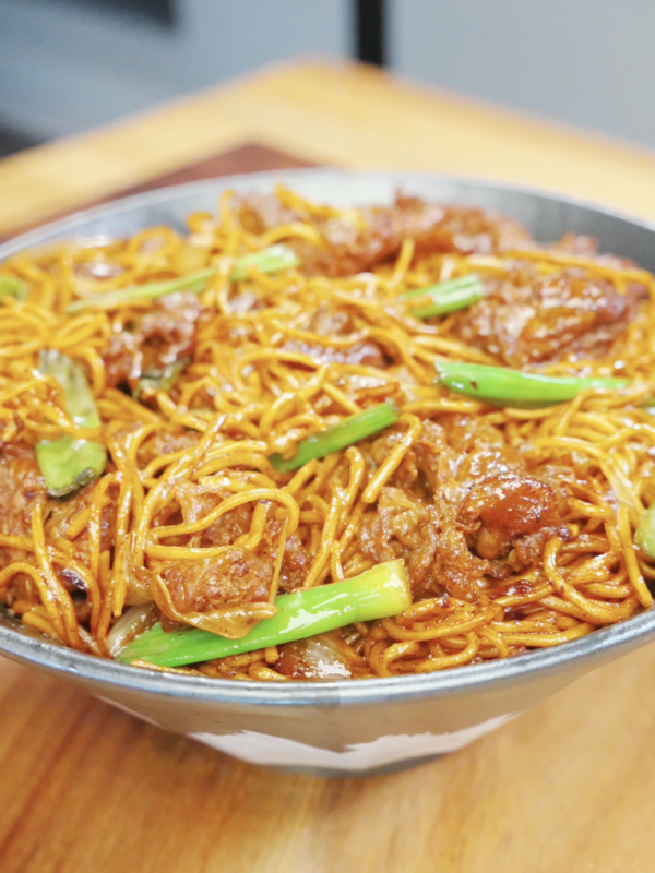 Bowl of beef chow mein with noodles, onions, and scallions tossed in a rich glossy sauce in the Beef Chow Mein Recipe.