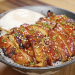 Sliced chicken bulgogi arranged over steamed white rice, coated in a caramelized glaze and topped with sesame seeds and scallions for a classic Korean-style bowl.