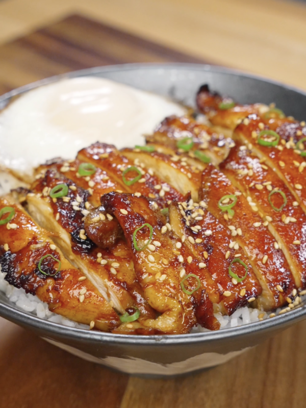 Sliced chicken bulgogi arranged over steamed white rice, coated in a caramelized glaze and topped with sesame seeds and scallions for a classic Korean-style bowl.
