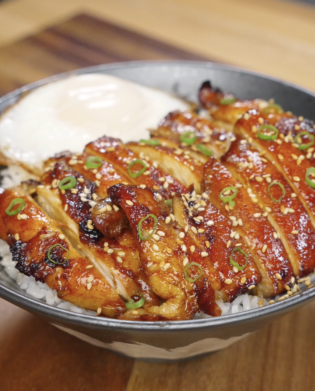 Sliced chicken bulgogi arranged over steamed white rice, coated in a caramelized glaze and topped with sesame seeds and scallions for a classic Korean-style bowl.