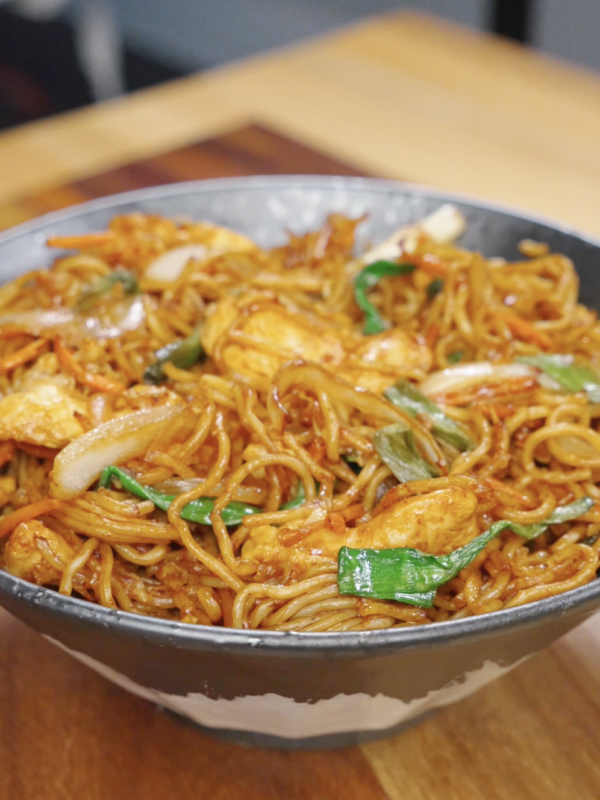 Chicken chow mein served in a bowl with stir-fried noodles, tender chicken, cabbage, carrots, and scallions coated in a glossy soy-based sauce.