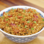 Bowl of garlic bacon fried rice topped with crispy bacon pieces and fresh scallions.