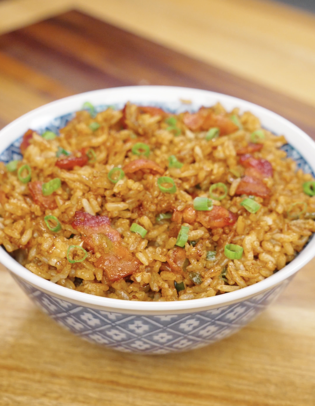 Bowl of garlic bacon fried rice topped with crispy bacon pieces and fresh scallions.