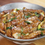 Bowl of Mongolian beef stir fry with tender beef slices, sautéed onions, and scallions coated in a rich, glossy sauce from this Mongolian Beef Recipe.