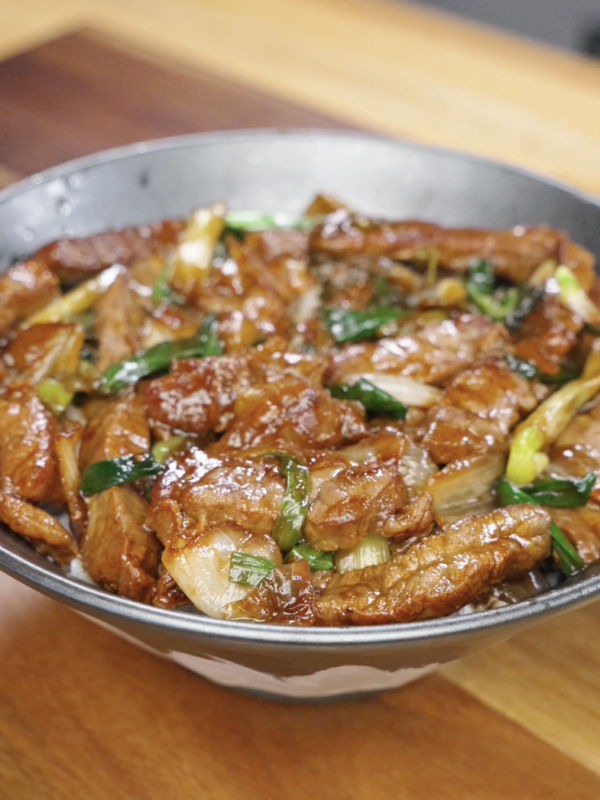 Bowl of Mongolian beef stir fry with tender beef slices, saut&eacute;ed onions, and scallions coated in a rich, glossy sauce from this Mongolian Beef Recipe.