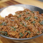 Thai basil ground beef served over white rice with a fried egg, showcasing a rich, glossy sauce and fresh basil.