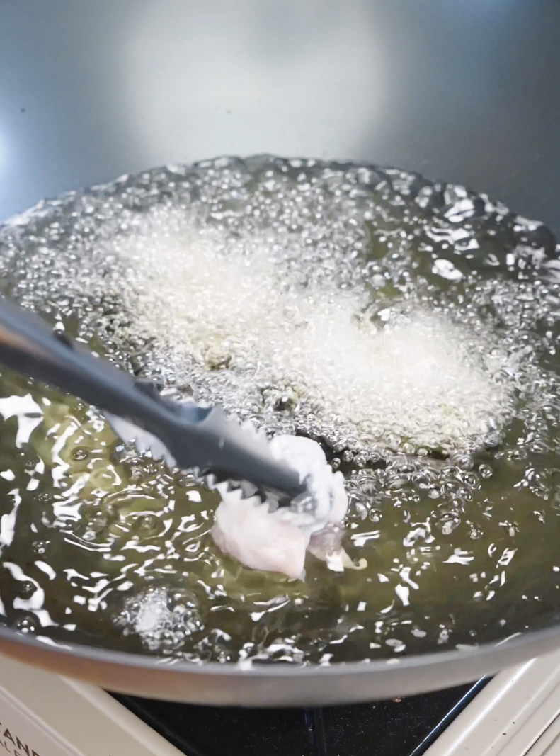 Battered chicken pieces being lowered into hot oil, frying until golden and crispy for the Honey Butter Fried Chicken Recipe.
