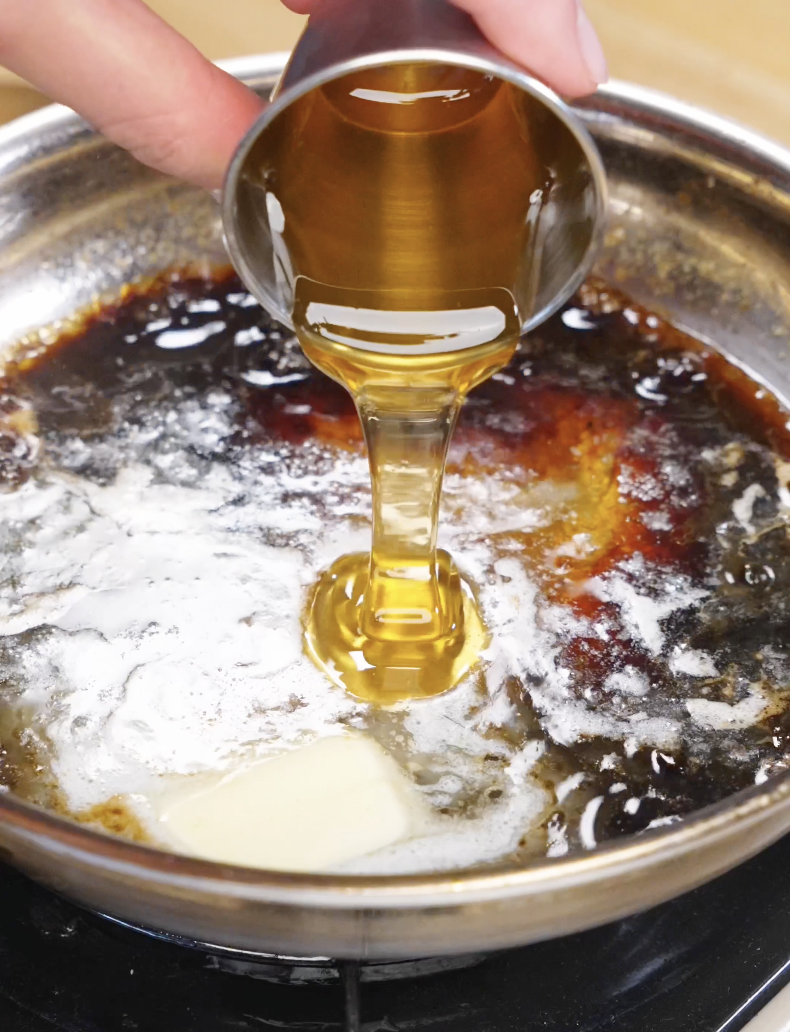 Honey being poured into a pan with butter and soy sauce, creating a glossy sauce for the Honey Butter Fried Chicken Recipe.