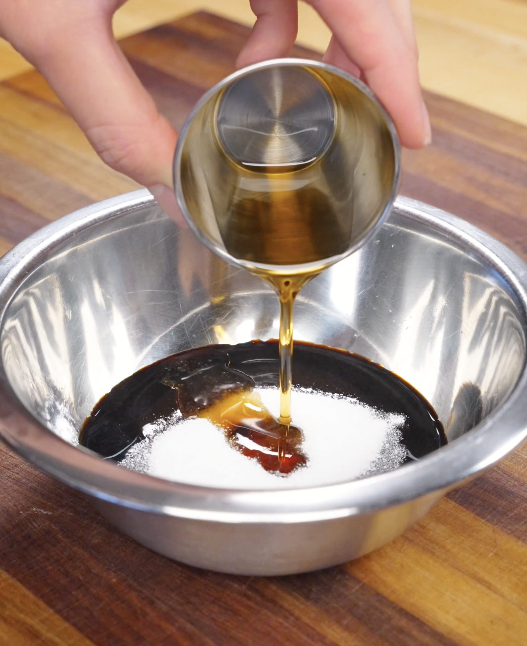 Honey being poured into a stainless steel bowl with soy sauce, sugar, and oyster sauce to create a glossy garlic beef fried rice sauce with a balanced sweet and savory flavor.