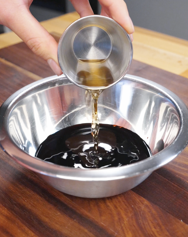 Soy-based fried rice sauce being poured into a bowl, combining dark soy sauce, light soy sauce, and seasonings.