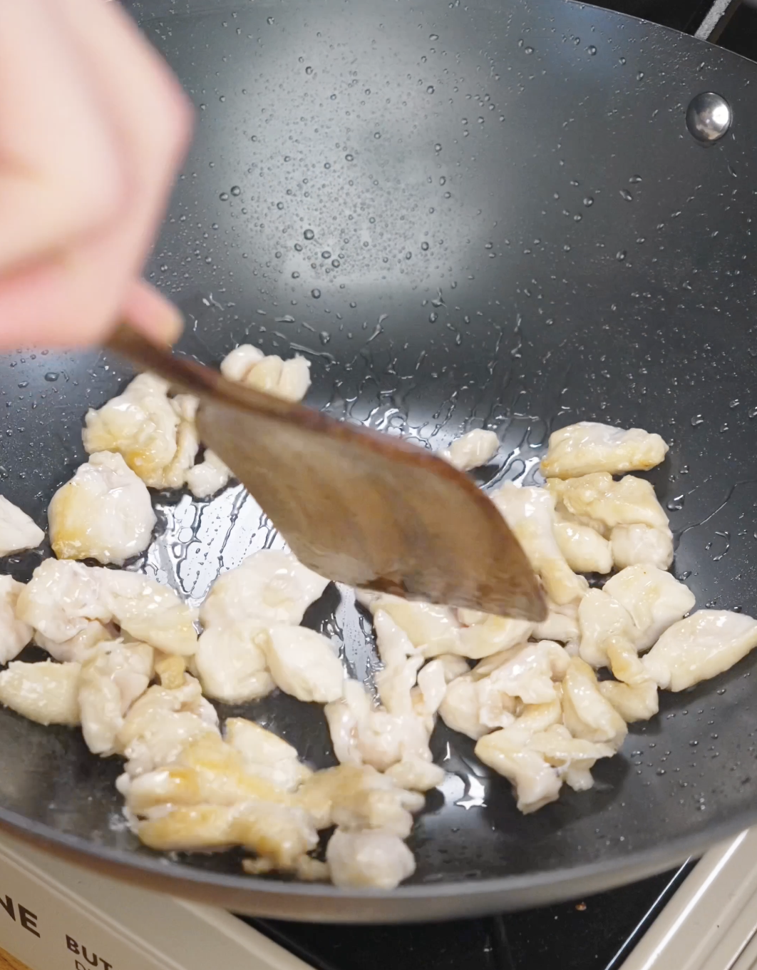 Marinated chicken cooking in a pan until lightly browned for garlic chicken noodles.